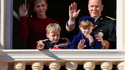 Fürstin Charlène von Monaco (hinten l), Fürst Albert II. von Monaco (hinten r), Fürst Jacques von Monaco (vorne l) und Fürstin Gabriella (vorne r) winken vom Balkon des Fürstenpalastes von Monaco während einer Zeremonie zum Nationalfeiertag in Monaco am 19. November 2023.