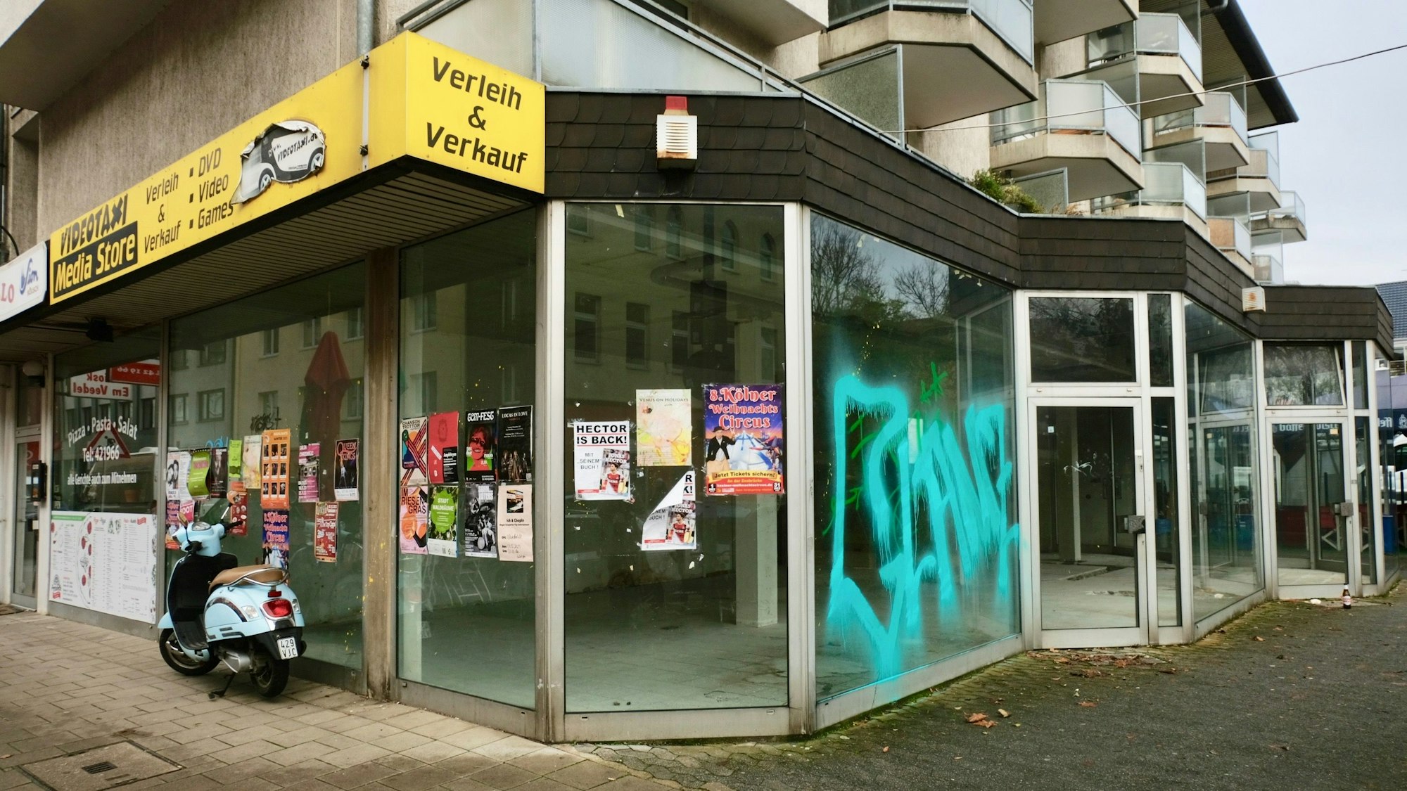 Glasfront eines Ladenlokals, mit Plakaten beklebt und Graffiti beschmiert.