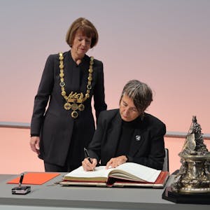 10.12.2023 Dr. Monika Hauser trägt sich in das goldene Buch der Stadt ein. Dabei OB Henriette Reker.
