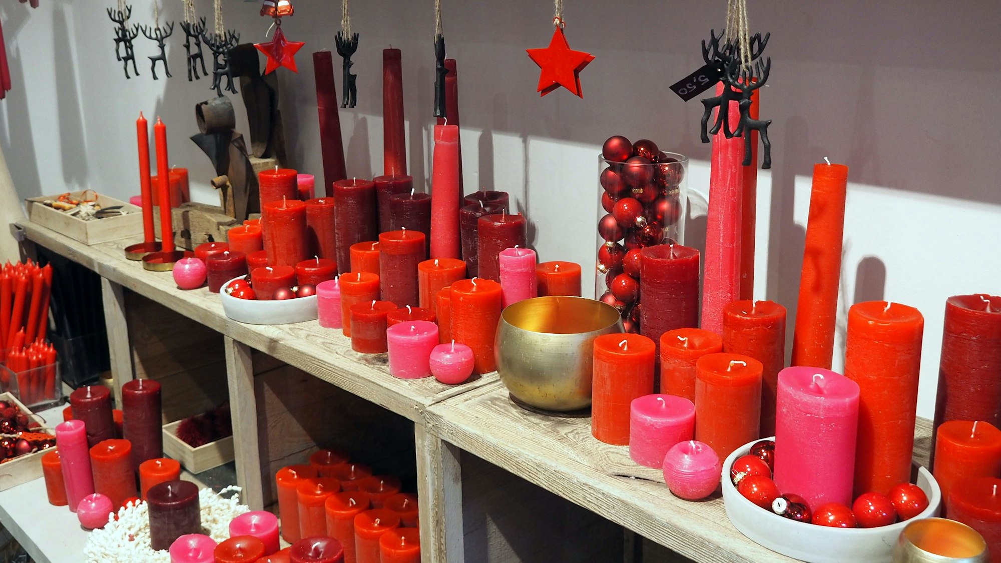 Ein Regal mit vielen Kerzen in Rottönen.