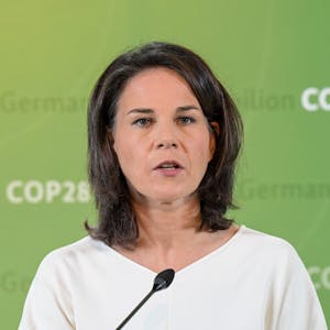 Annalena Baerbock (Bündnis 90 / Die Grünen) steht vor einer grünen Wand mit dem sich wiederholenden Aufdruck „German Climate Pavilion COP28 Dubai 2023“.