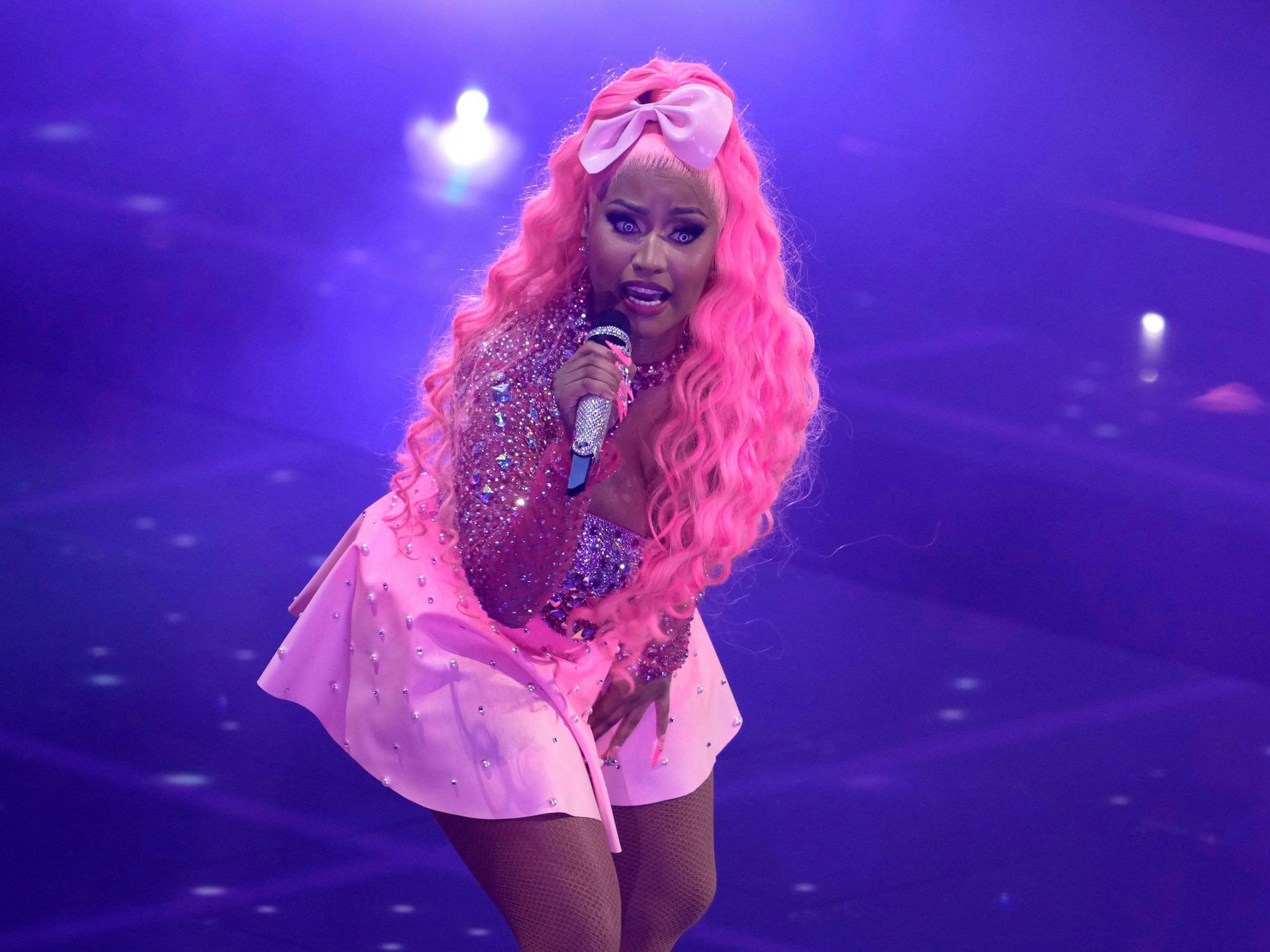 Nicki Minaj performt mit Mikrofon auf der Bühne, ihre pinken Haare stechen ins Auge.
