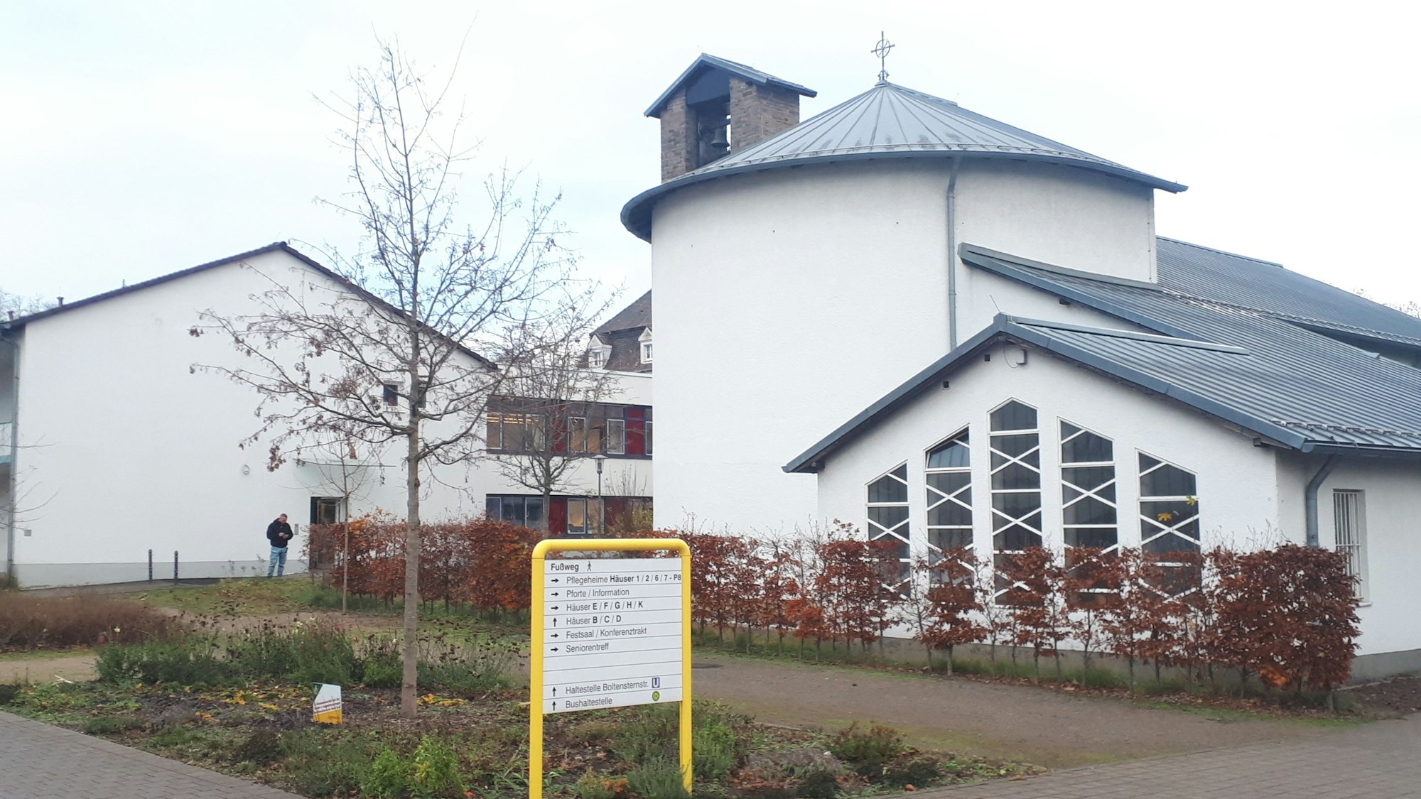 Ein weißes Kirchengebäude mit einem gelben Wegweiser im Vordergrund