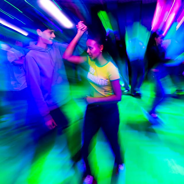 Charlise mit Tanzpartner Anton, eingetaucht in buntes Disco-Licht.
