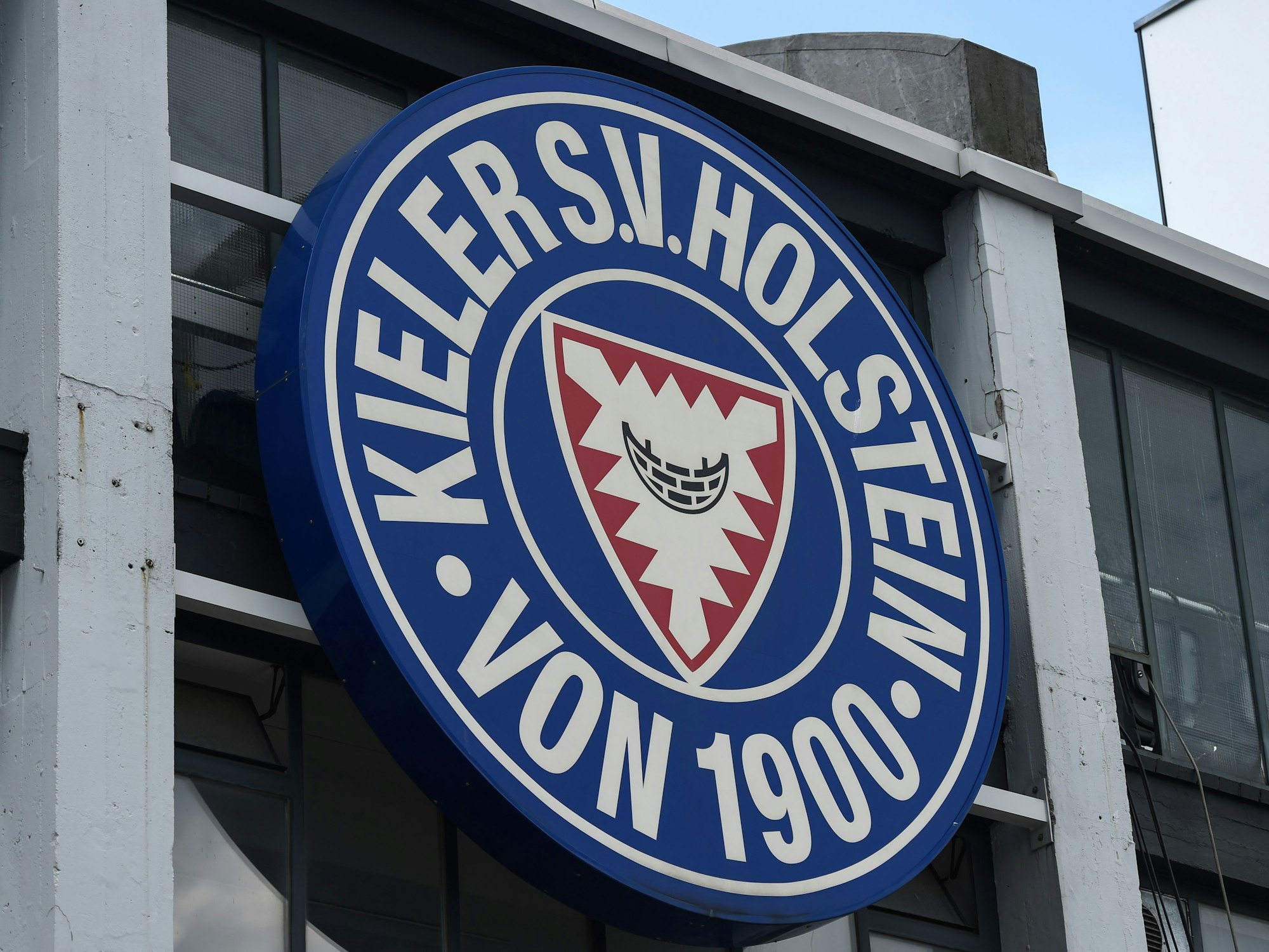 Das Logo des Fußballvereins Holstein Kiel ist außen auf dem Stadion zu sehen.