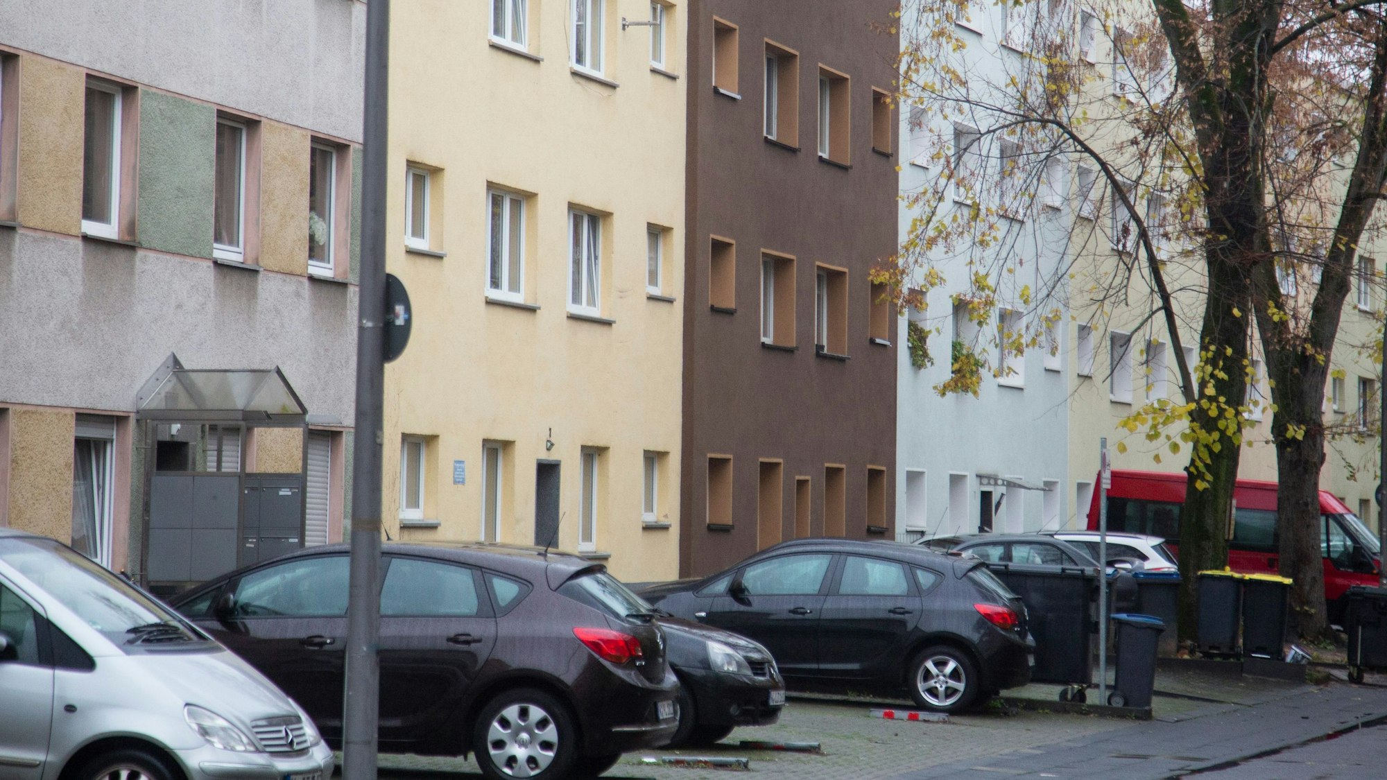 Vor einer Reihe mit Mehrfamilienhäusern sind Autos geparkt.