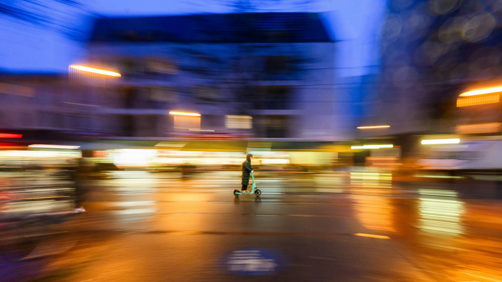 Eine Frau fährt am frühen Morgen mit einem Elektroroller.