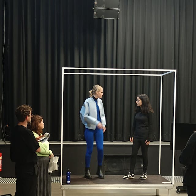Zu sehen sind zwei der Darsteller bei der Probe auf der Bühne.