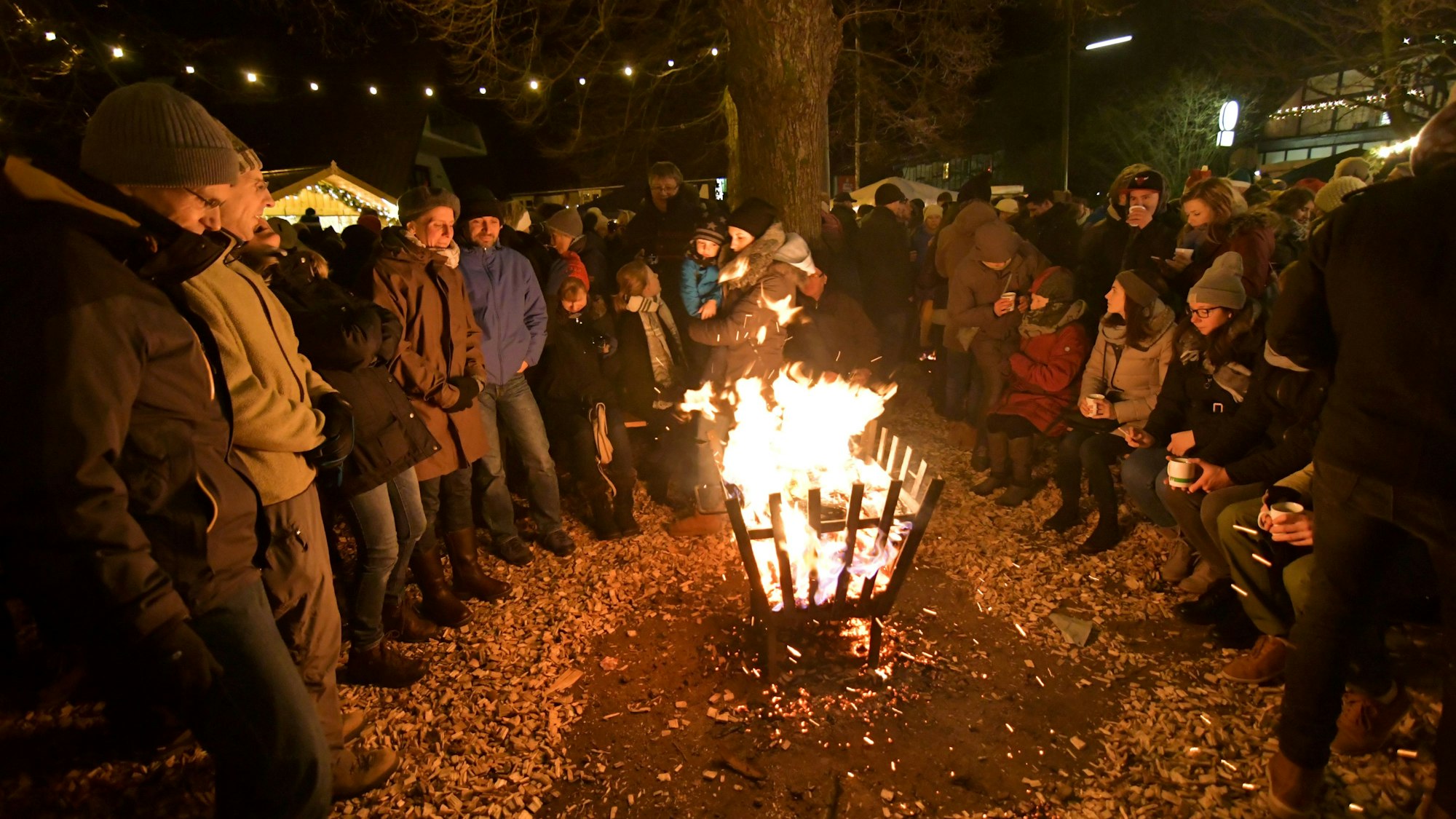 Menschen stehen am Abend um einen Feuerkorb auf dem Weihnachtsmarkt 2018 in Overath-Marialinden.