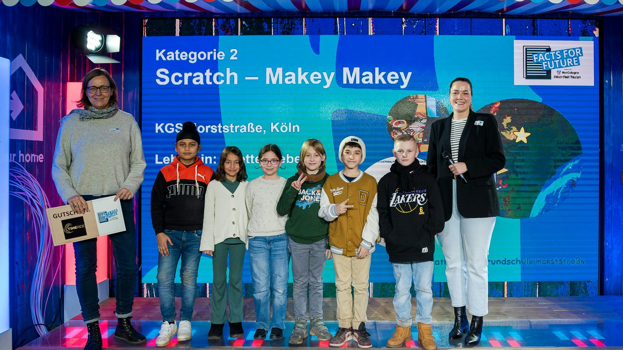 Annette Weber, stellvertretende Leiterin der Kölner KGS Horststraße, nahm den Preis mit ihren Schülerinnen und Schülern entgegen. Rechts: Katinka Kohn von der Netcologne-Kommunikation.