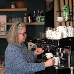 Eine Frau steht an einer Kaffeemaschine.