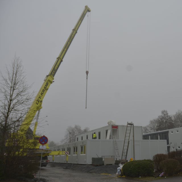 Container für die Unterbringung von Geflüchteten werden auf dem Parkplatz neben der kleinen Turnhalle an der Brionner Straße aufgebaut.