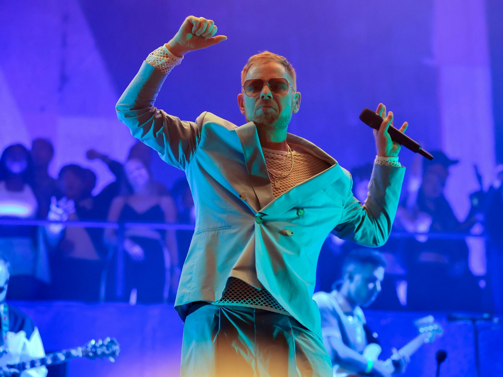 Peter Fox steht mit Sonnenbrille und Anzug auf der Bühne und tanzt zu einem Song.
