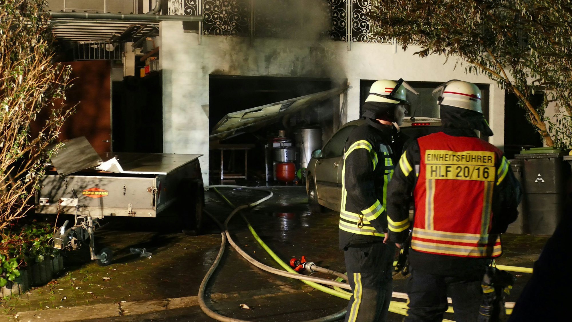 Feuerwehrleute stehen vor einer ausgebrannten Garage.