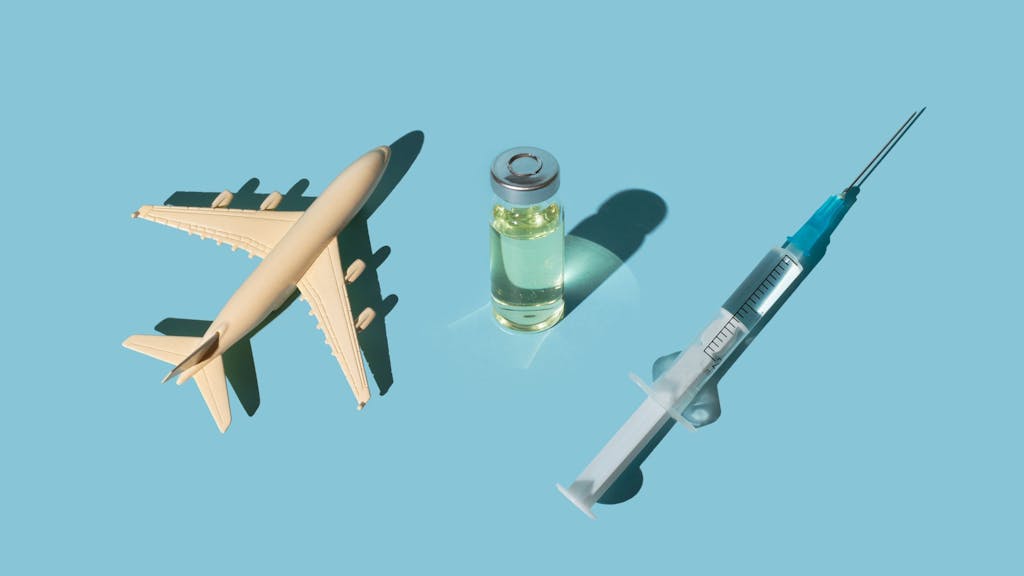 Vials, syringes with a vaccine and airplane on a blue background. Concept COVID-19 vaccine immunization and travel to the pandemic.