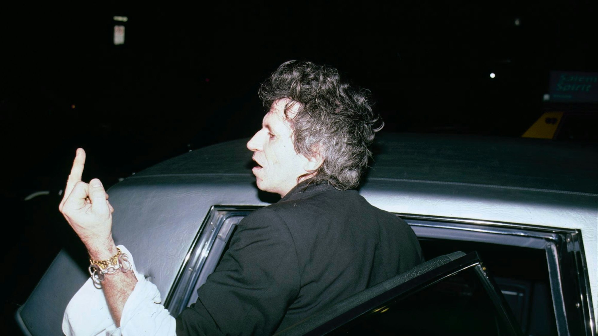 Keith Richards zeigt Fotografen den Stinkefinger, während er in ein Auto steigt.
