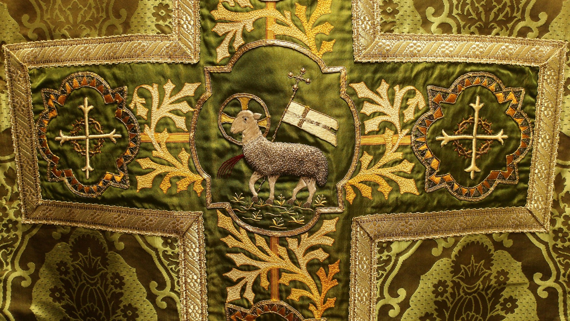 Das Bild zeigt eine wertvolle Stickerei mit einem Lamm in der Mitte.