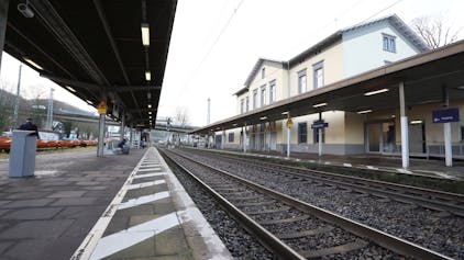 Zwischen einem überdachten Bahnsteig und dem Bahnhofsgebäude verlaufen die Gleise der rechtsrheinischen Bahntrasse.