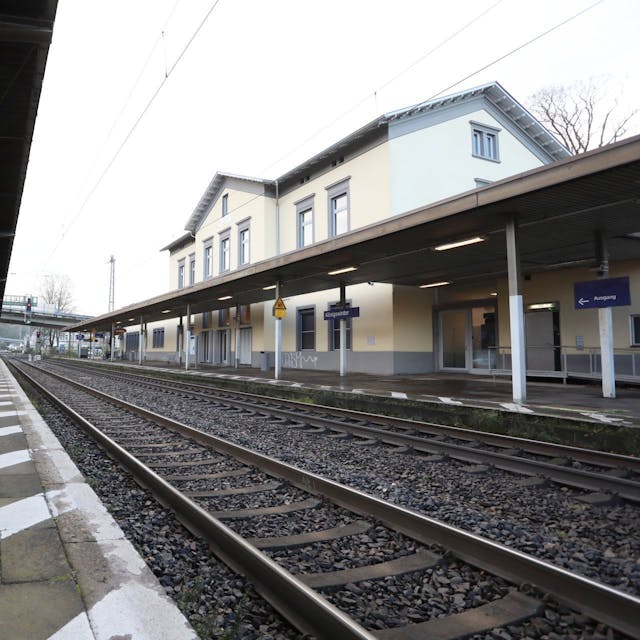 Zwischen einem überdachten Bahnsteig und dem Bahnhofsgebäude verlaufen die Gleise der rechtsrheinischen Bahntrasse.