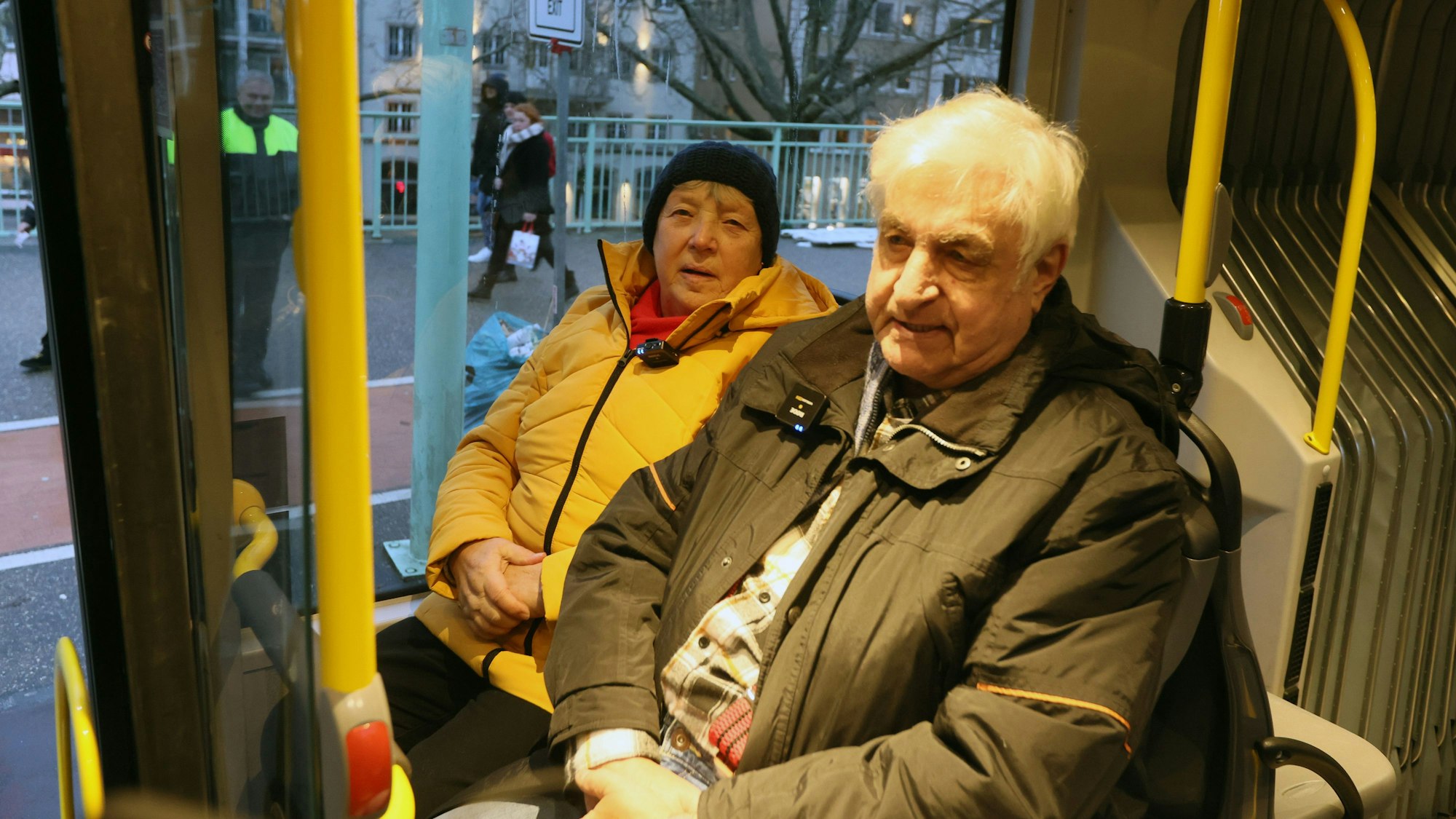 Das ältere Paar sitzt in dicken Winterjacken in einem Bus der KVB.