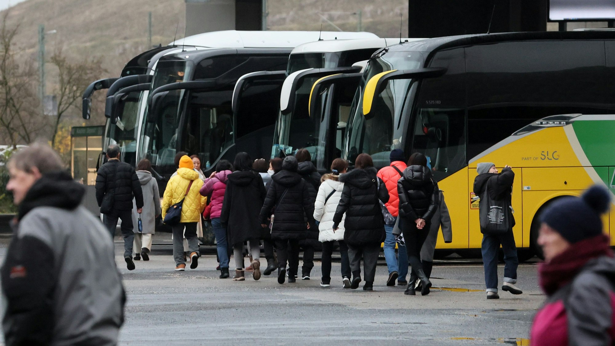 Parkplatz P22 in Deutz für Fernreisebusse: Touristen steigen in einen Reisebus ein.