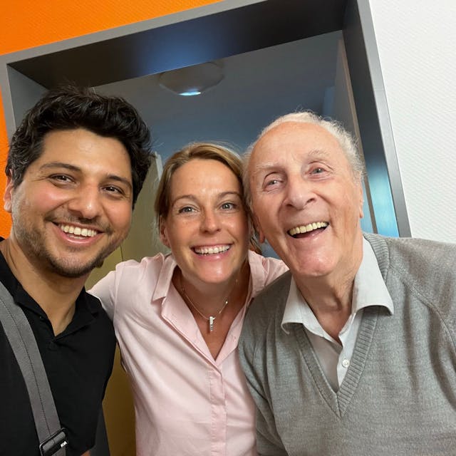 Zwei Filmemacher lächeln gemeinsam mit ihrem 93-jährigen Interviewpartner in die Kamera.