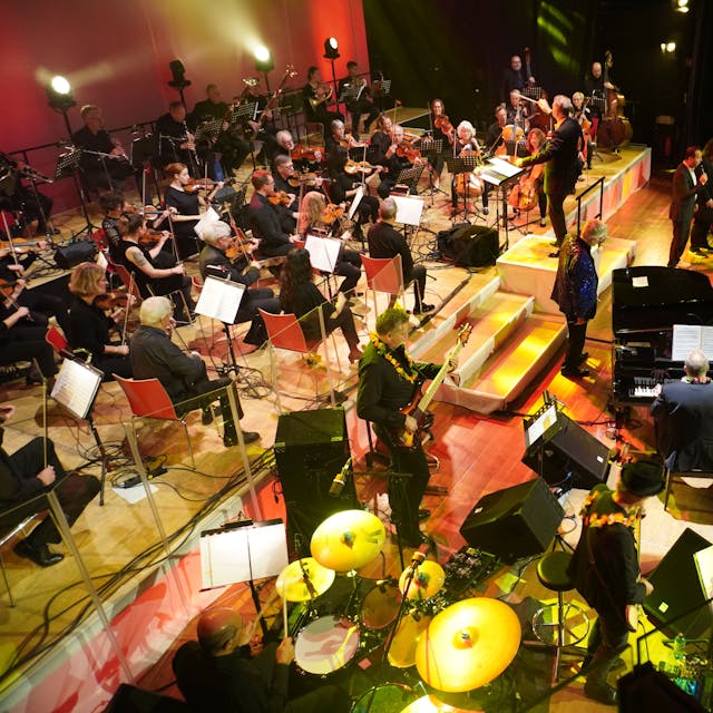 Eine Bühne mit klassischen Orchestermusikern und&nbsp; einer Band.