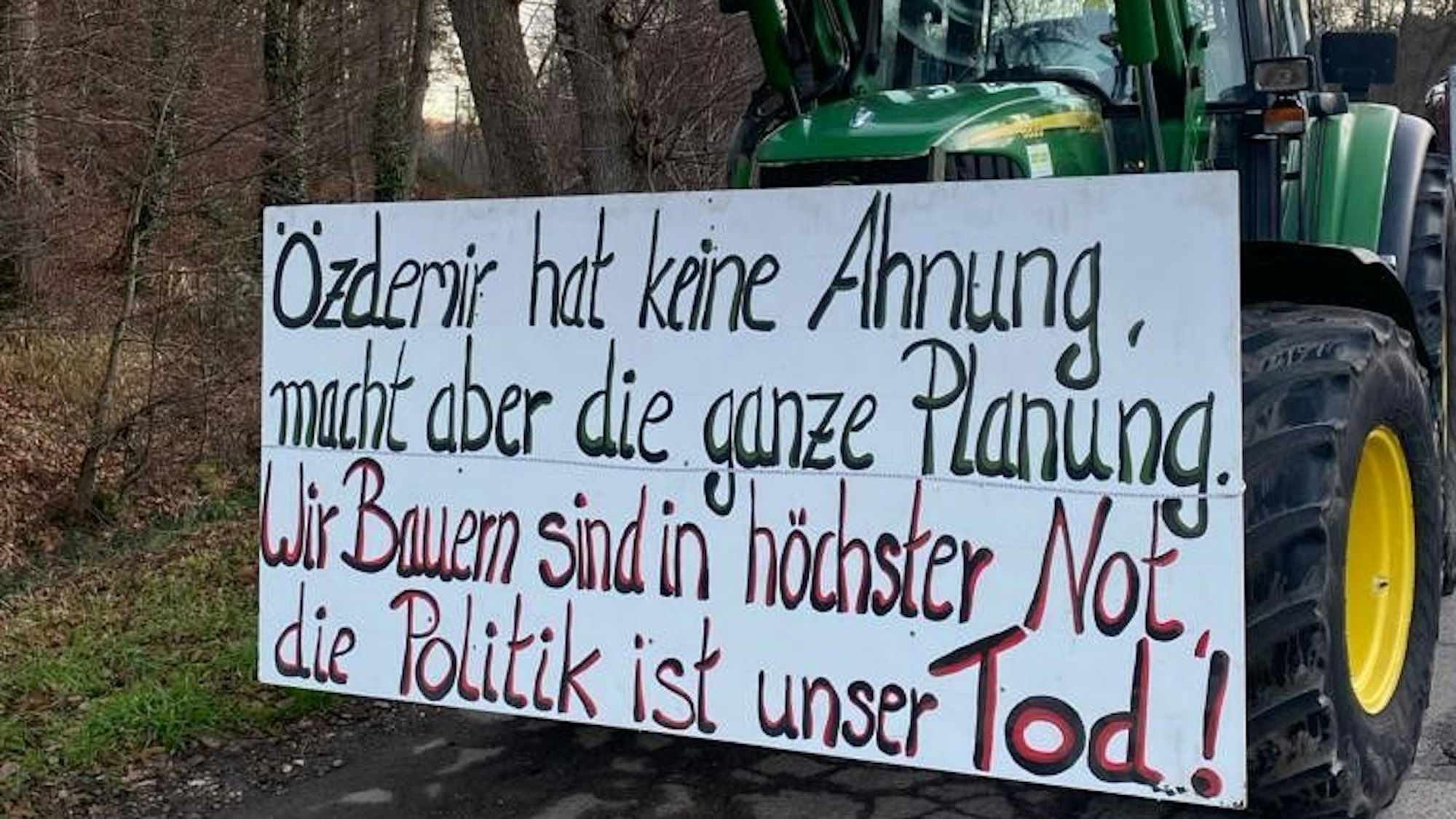 Ein Traktor aus einem Lichterzug trägt ein Plakat mit der Aufschrift „Özdemir hat keine Ahnung, macht aber die ganze Planung. Wir Bauern sind in höchster Not, die Politik ist unser Tod“.