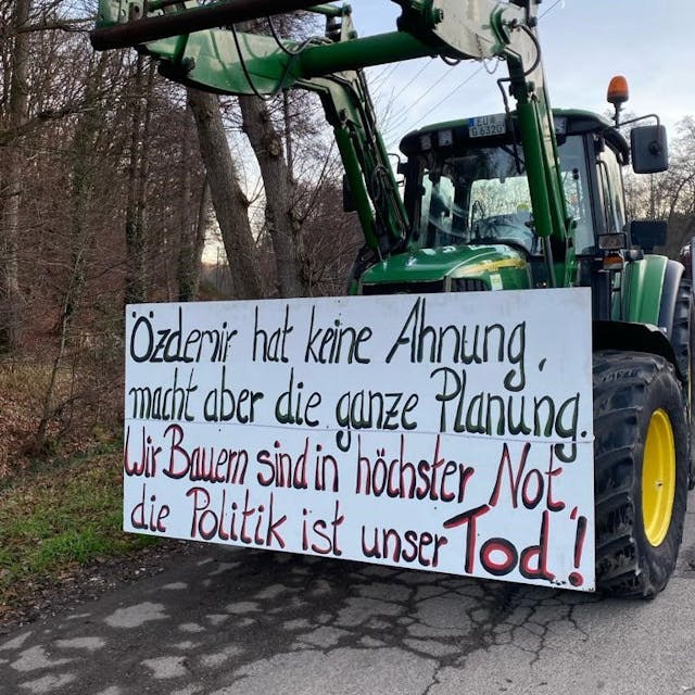 Ein Traktor aus einem Lichterzug trägt ein Plakat mit der Aufschrift „Özdemir hat keine Ahnung, macht aber die ganze Planung. Wir Bauern sind in höchster Not, die Politik ist unser Tod“.