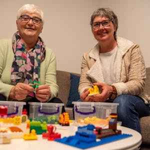Das Bild zeigt Anita Sauer (l.) und Vera Schröder auf einem Sofa sitzend. Vor ihnen steht auf einem Tisch Lego-Spielzeug.