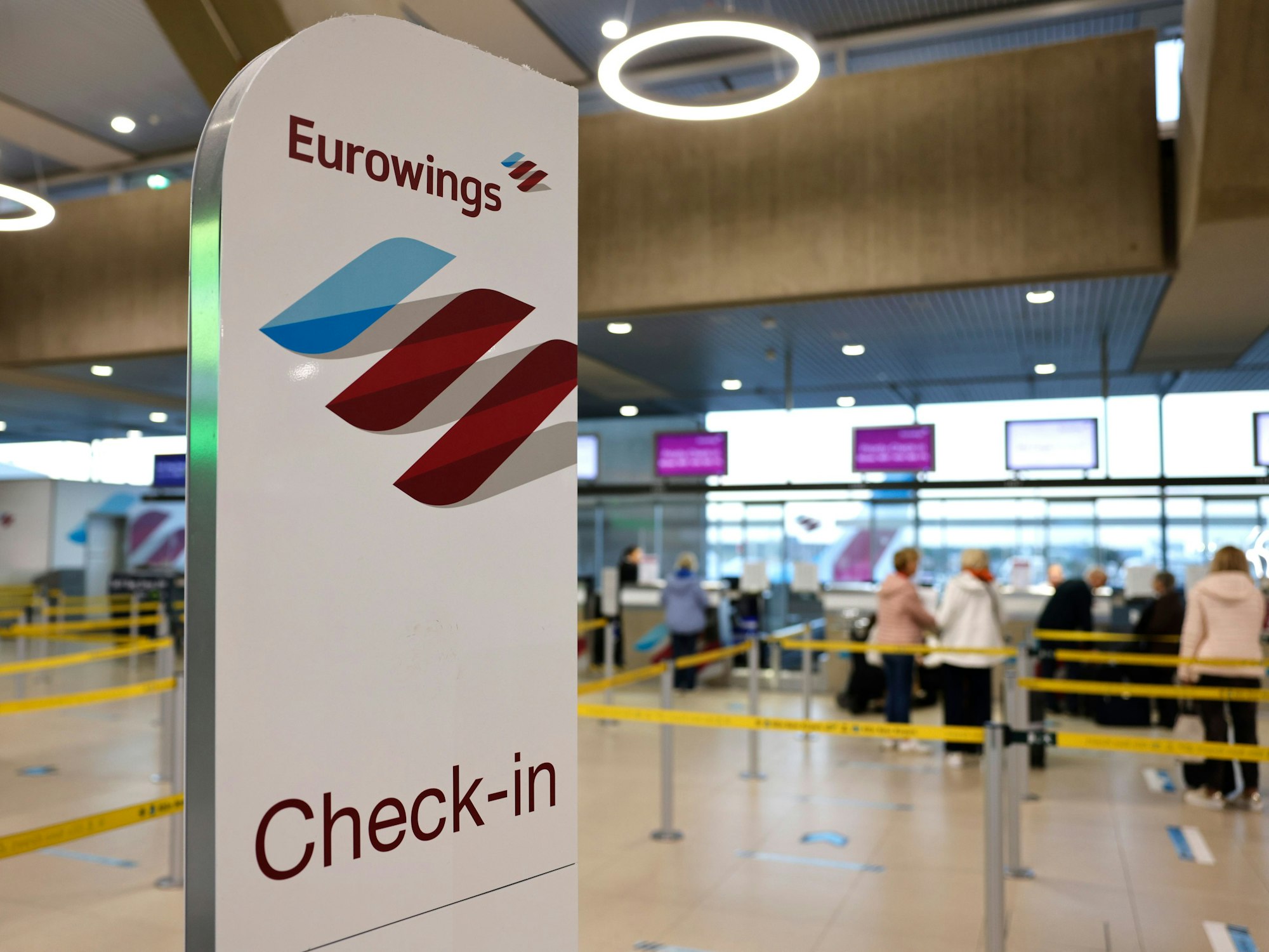 Reisende am Flughafen Köln/Bonn stehen in der Abflughalle an den Check-in-Schaltern der Airline Eurowings, hier im Oktober 2022.