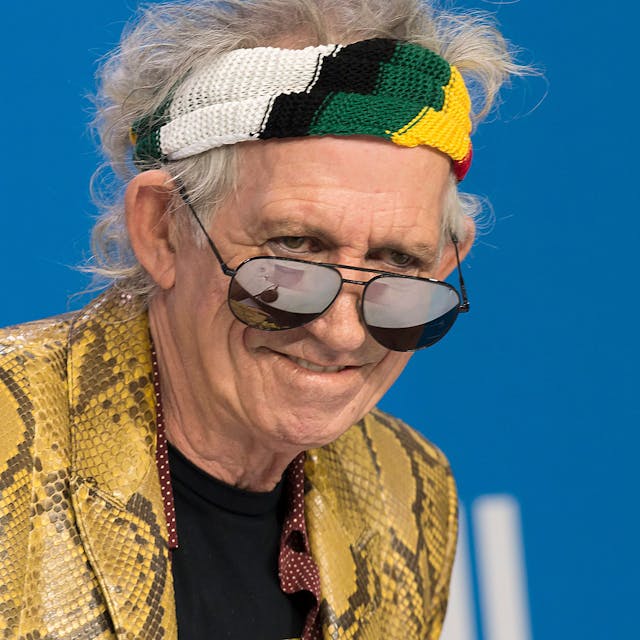 Keith Richards schaut über seine Sonnenbrille und trägt ein buntes Stirnband.