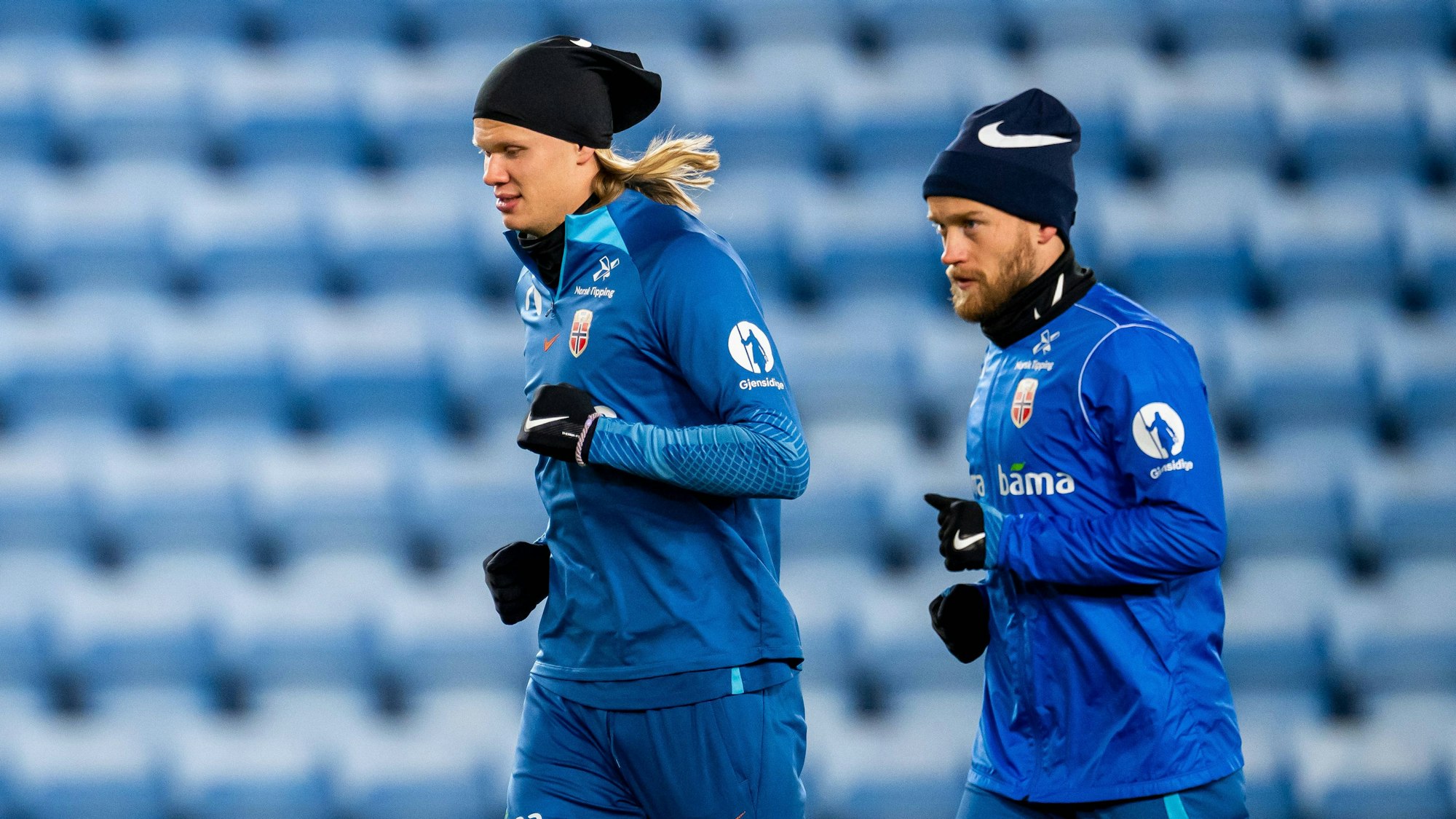 Bard Finne (r.) läuft beim Training der norwegischen Nationalmannschaft neben Superstar Erling Haaland. Beide tragen Handschuhe und eine Mütze.