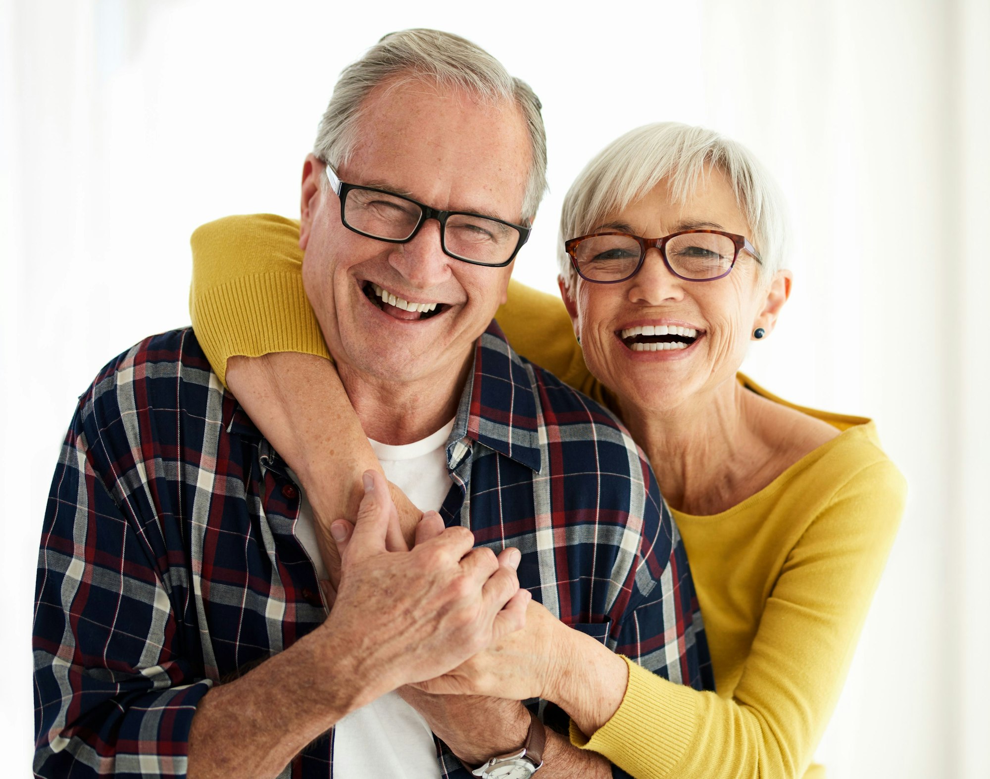 Seniorenpaar lacht fröhlich in die Kamera.