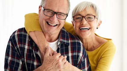 Seniorenpaar lacht fröhlich in die Kamera.