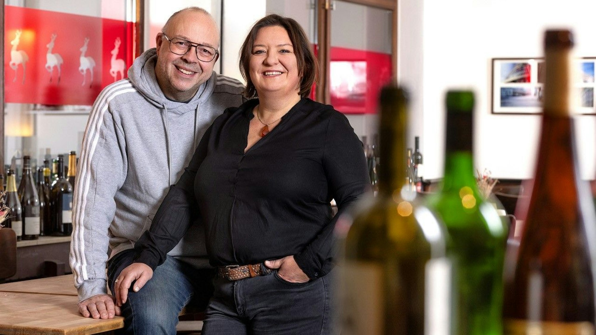 Andreas Esser und Iris Giessauf an ihrer Theke, im Vordergrund Weinflaschen.