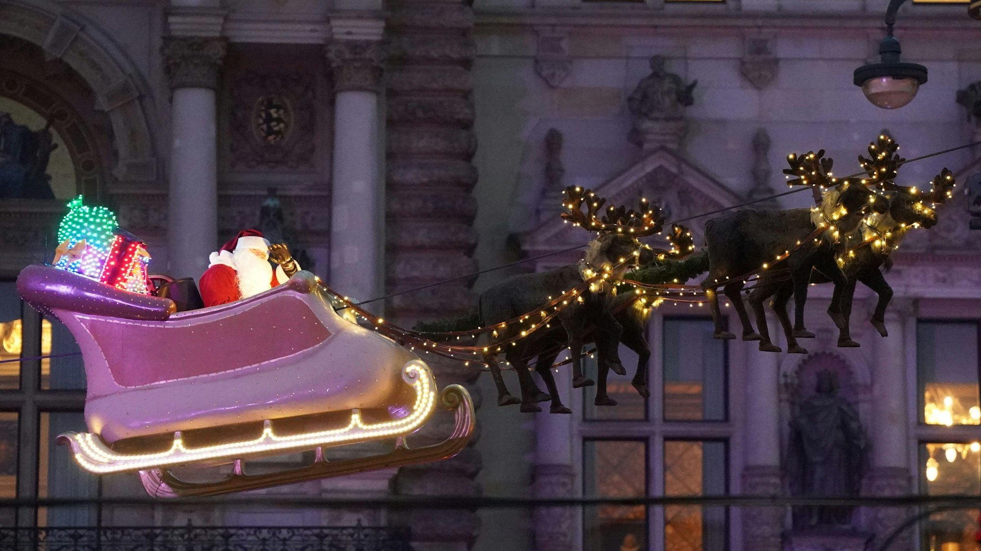 Der Weihnachtsmann schwebt im Schlitten mit seinen Rentieren über den Roncalli Weihnachtsmarkt auf dem Rathausmarkt in der Hamburger Innenstadt.