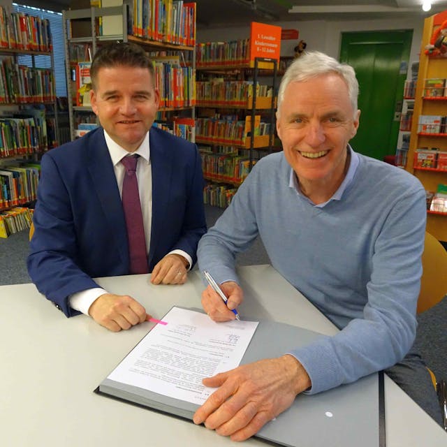 Bürgermeister Holger Jung (links) und sein Alfterer Kollege&nbsp; Dr. Rolf Schumacher unterzeichnen den Vertrag in den Räumen der Meckenheimer Bücherei.