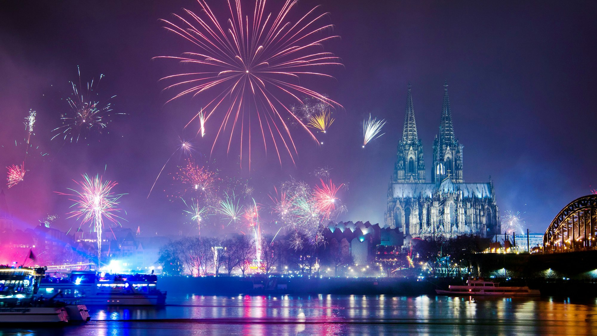 Feuerwerk ist in der Silvesternacht am Rhein über dem Dom zu sehen.