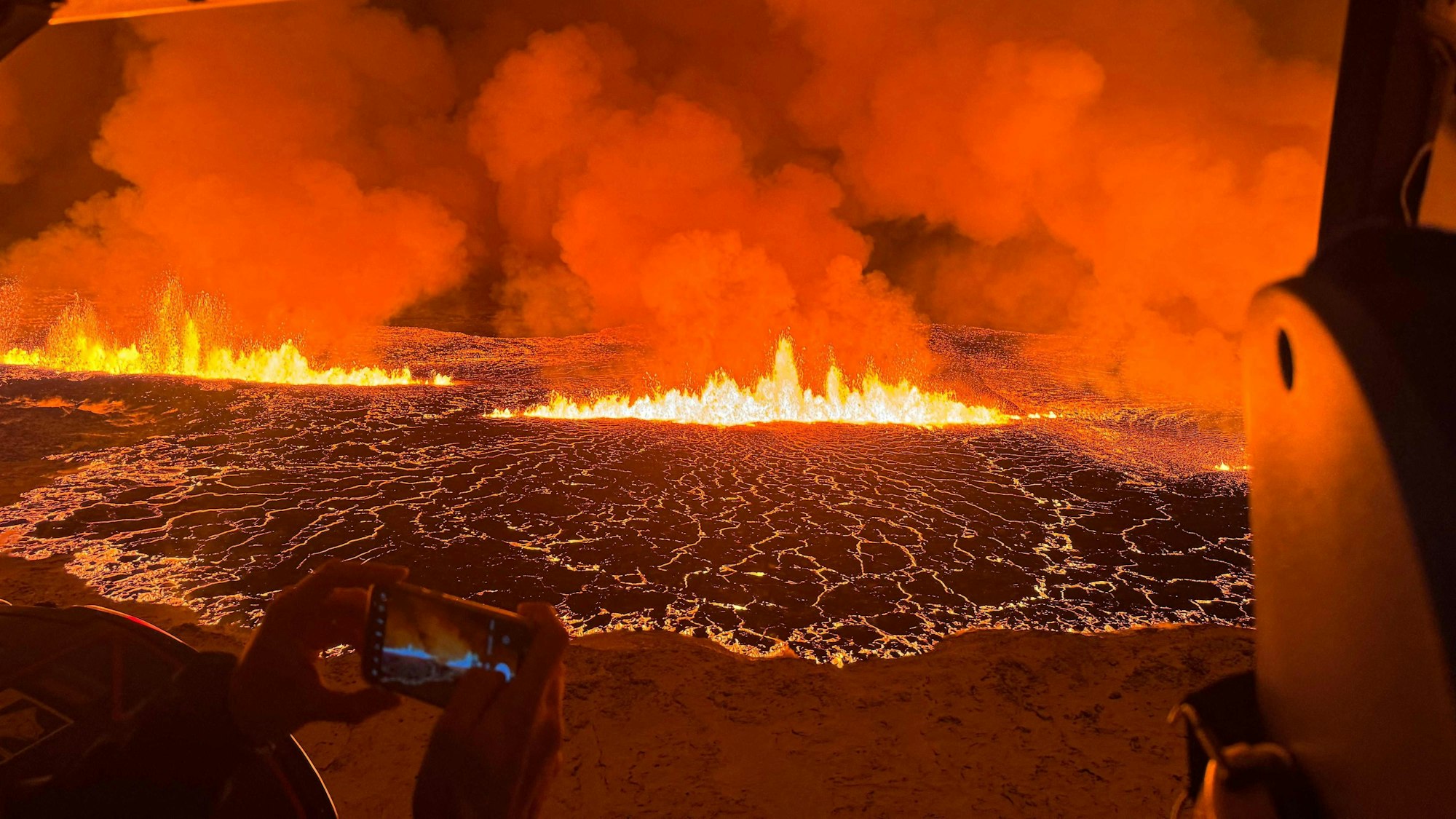 Vulkanausbruch auf Island: Personen beobachten Feuer, Magma und Rauch aus einem Helikopter.