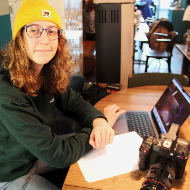 Lisa Stangenberg sitzt an einem Tisch, mit Kamera, Laptop und Film-Skript.