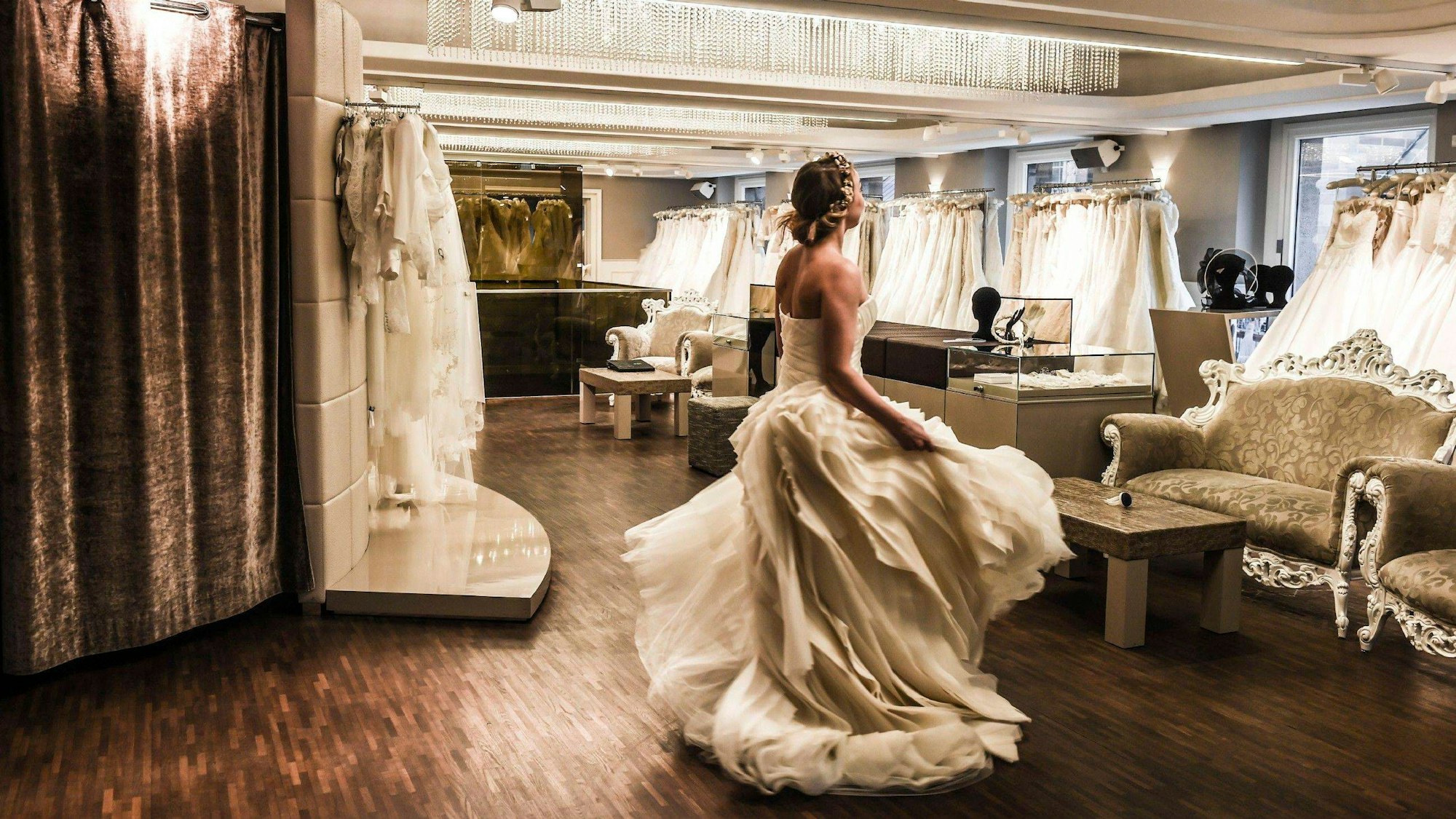 Eine Frau im Brautkleid steht in einem Brautmode-Laden und dreht sich.
