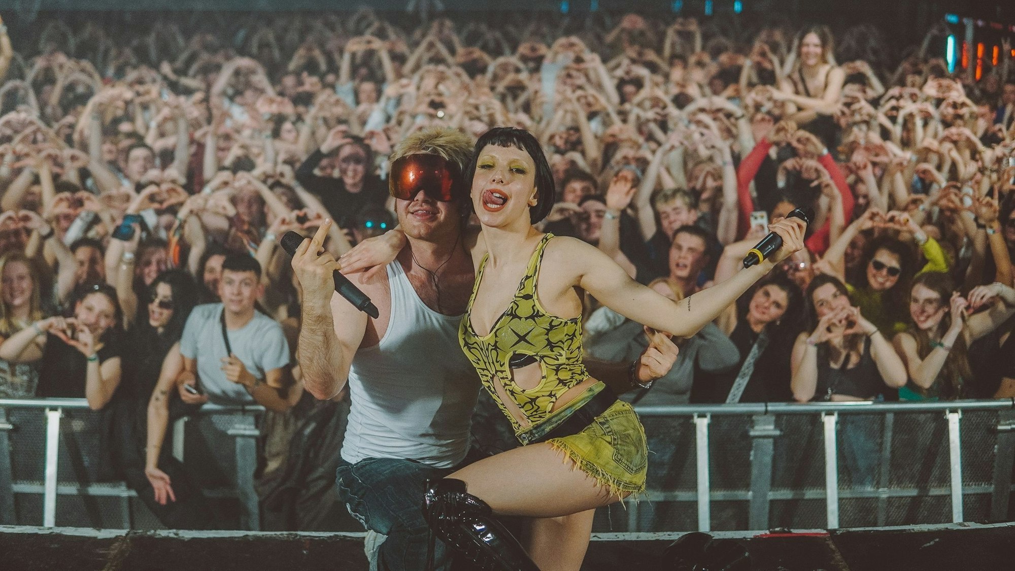 Die Sängerin Domiziana und der Rapper Ski Aggu, beide aus Berlin, posieren im April 2023 auf der Bühne des Kölner Popfestivals c/o pop vor gestikulierenden Fans.