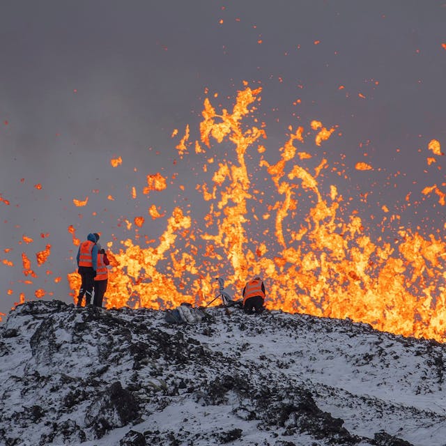 Wissenschaftler der Universität von Island nehmen Messungen und Proben, während sie auf dem Kamm vor dem aktiven Teil der Eruptionsspalte eines aktiven Vulkans in Grindavik auf der isländischen Halbinsel Reykjanes stehen.