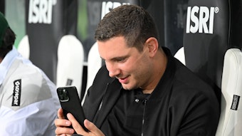 Nils Schmadtke schaut begeistert auf sein Smartphone.