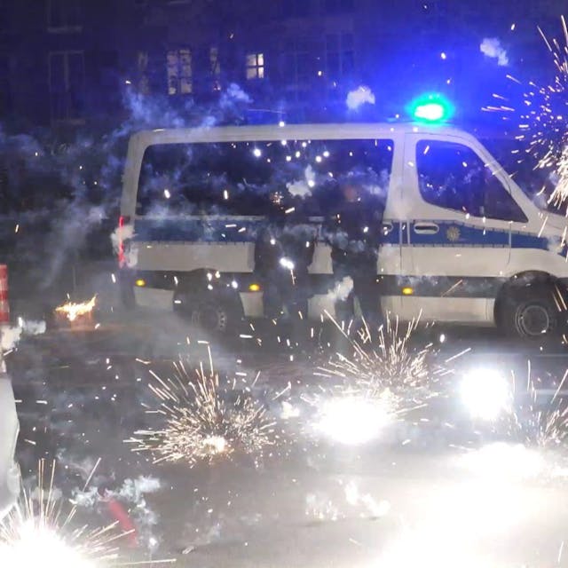 Polizeibeamte stehen am Silvesterabend 2022 hinter explodierendem Feuerwerk. Vergangenes Silvester kam es vor allem in&nbsp;Berlin zu Ausschreitungen: Junge Männer randalierten mit Böllern und Raketen, attackierten Einsatzkräfte.