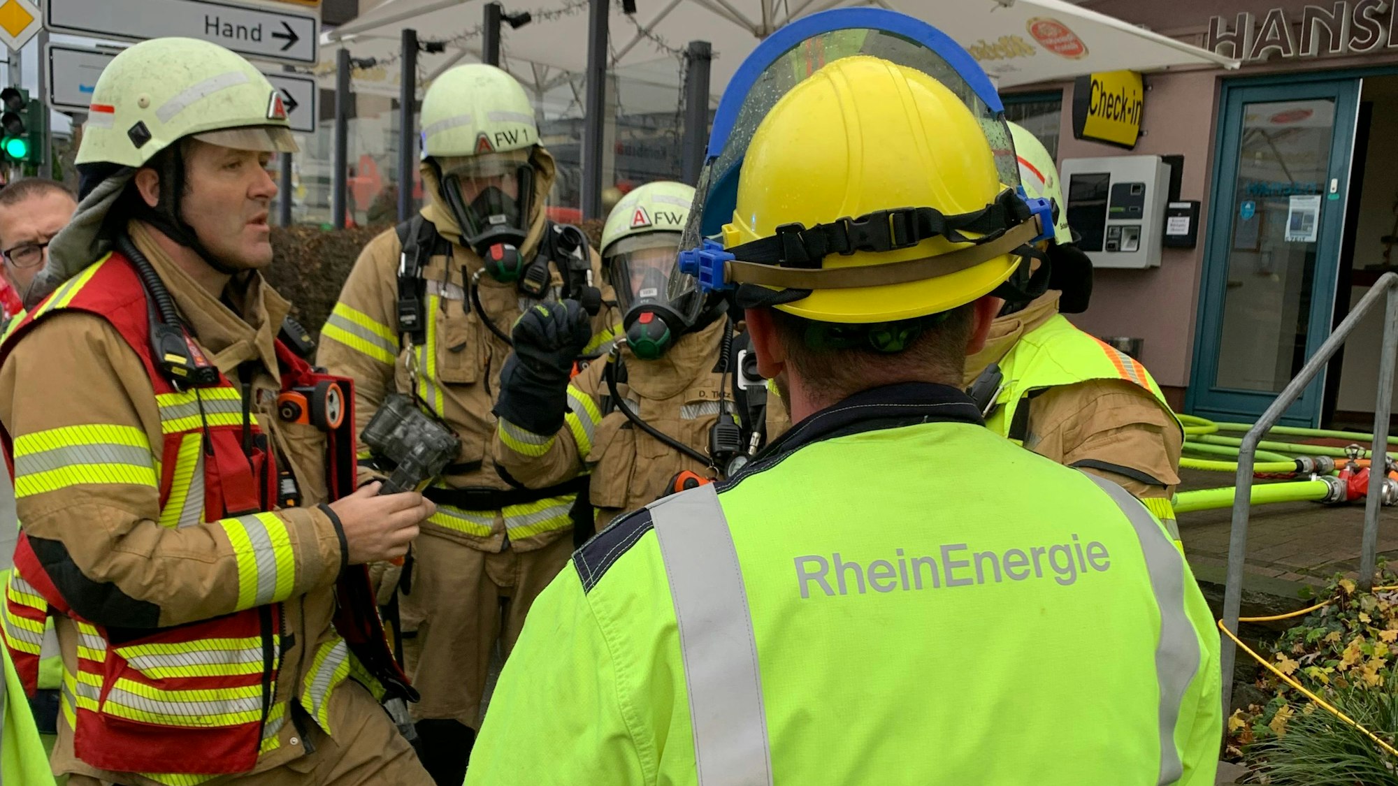 Feuerwehrleute und ein Mitarbeiter des Energieversorgers Rheinenergie stehen an eine Einsatzstelle.
