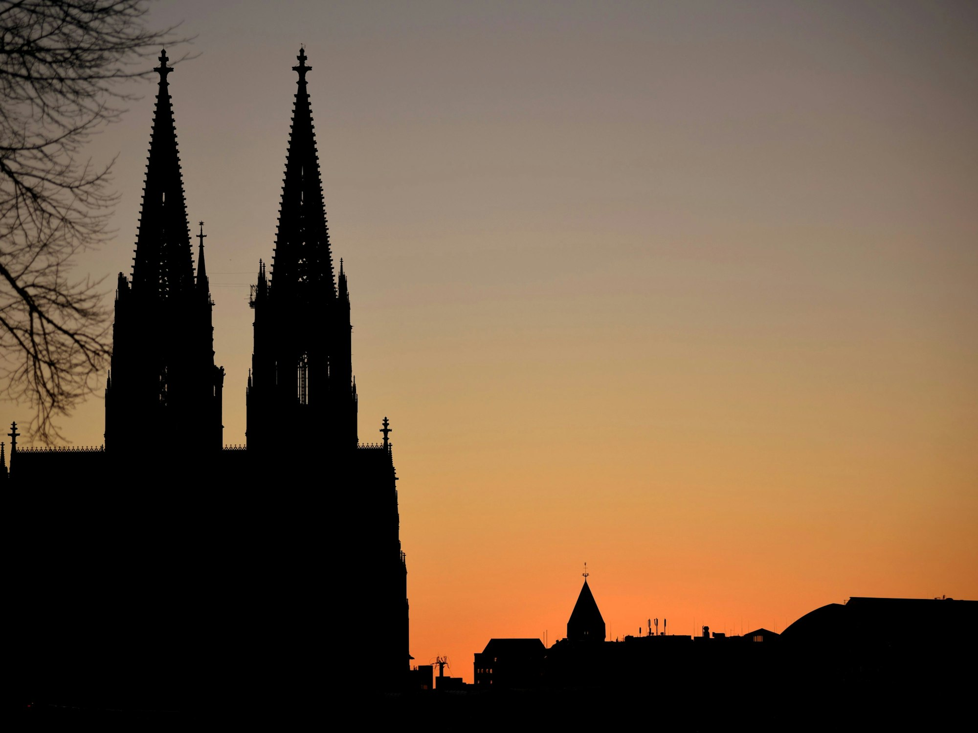 Sonnenuntergang von Deutz aus fotografiert bei wolkenlosem Himmel mit dem Kölner Dom und der Turmspitze von St. Andreas im Hintergrund.