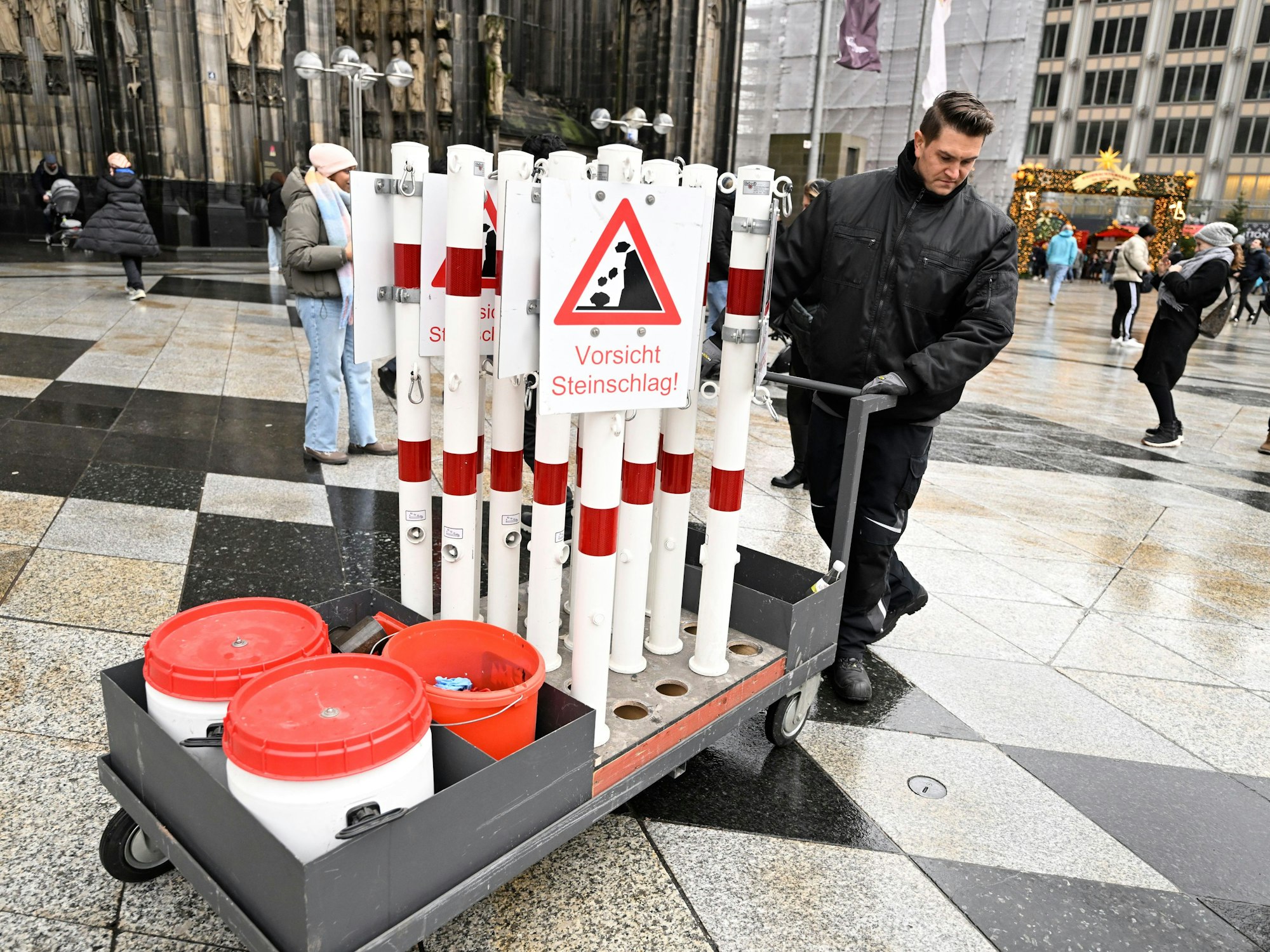 Ein Mitarbeiter der Stadt Köln stellt Schilder auf, die vor Steinschlag warnen.