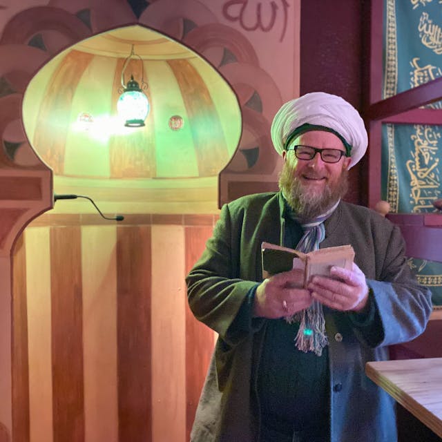 Ahmad Adamek trägt Gebetsmütze und Turban. Er liest in der osmanischen Herberge in Kall-Sötenich aus dem Koran.